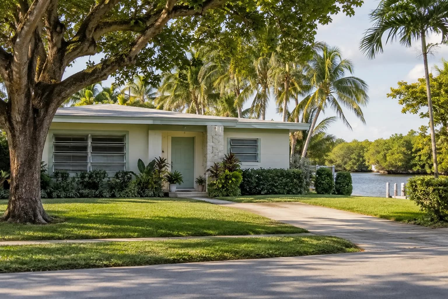 An older El Portal home with jalousie windows under shade trees