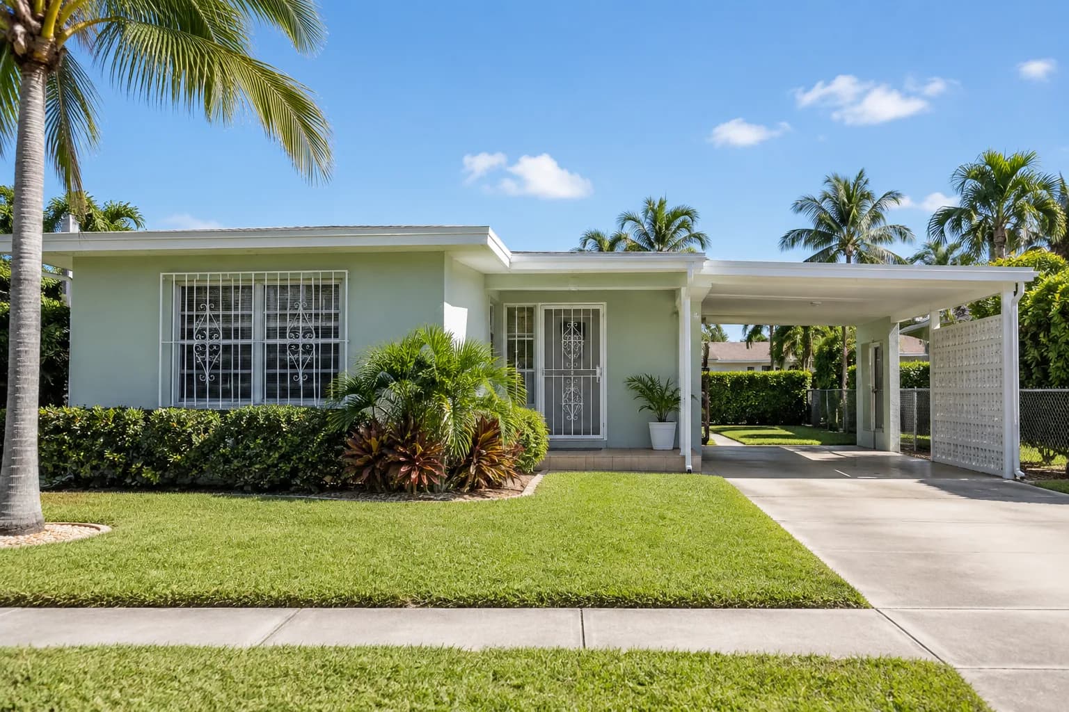 A Hialeah concrete block home with clean windows and a carport