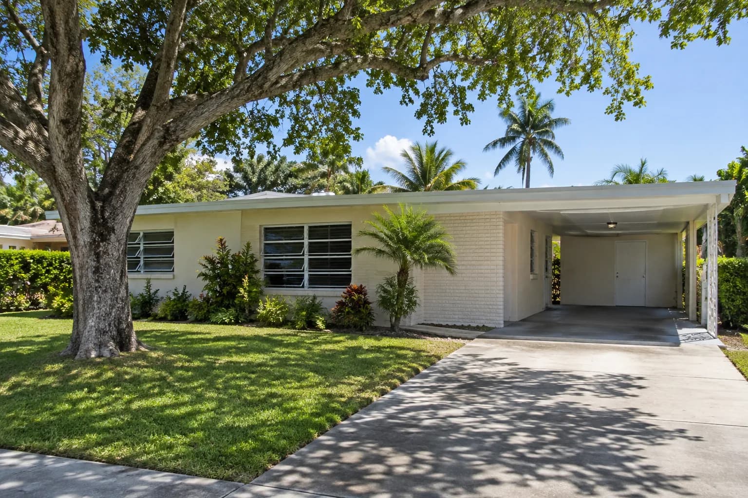 A single-story Miami Gardens home with jalousie windows and a carport