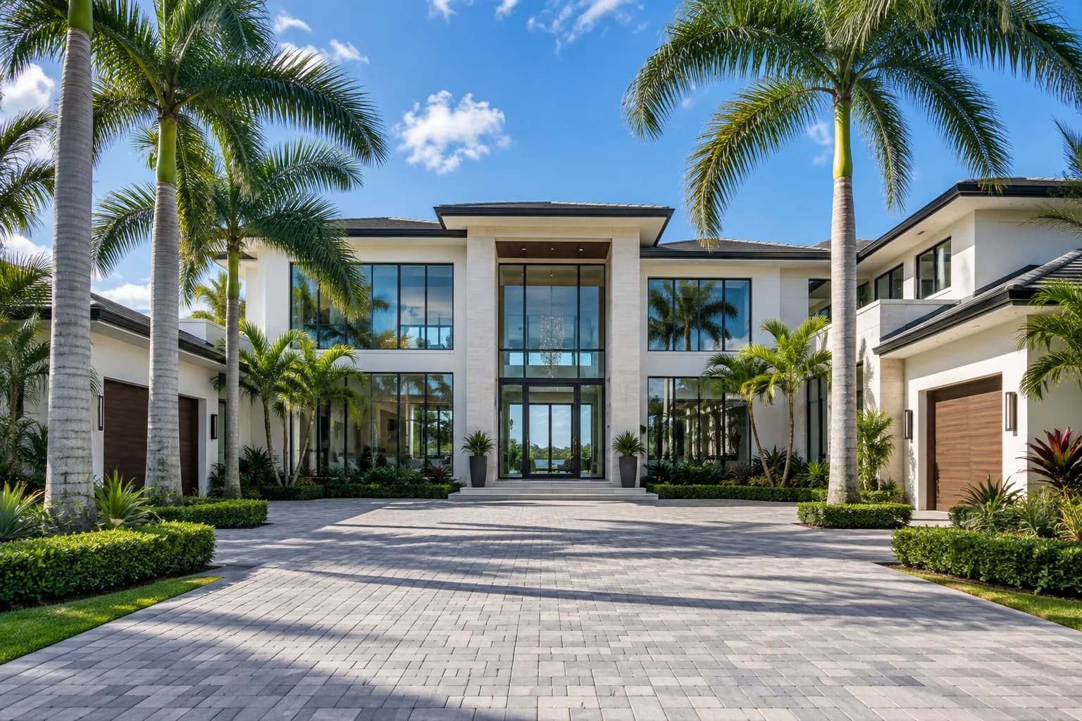 A large two-story Parkland home with tall entry windows and a paver driveway