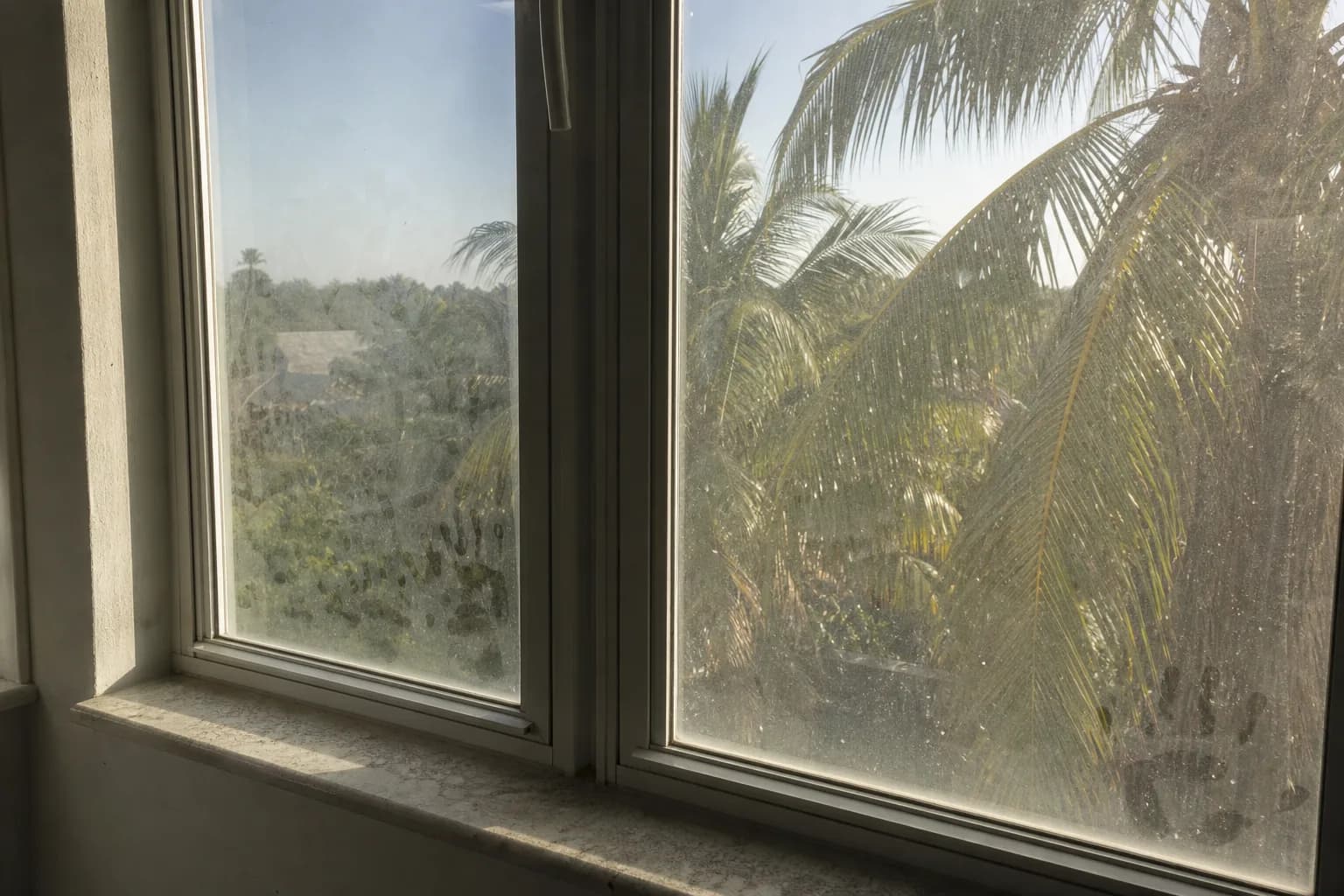 Interior window glass with film, smudges and a dusty sill