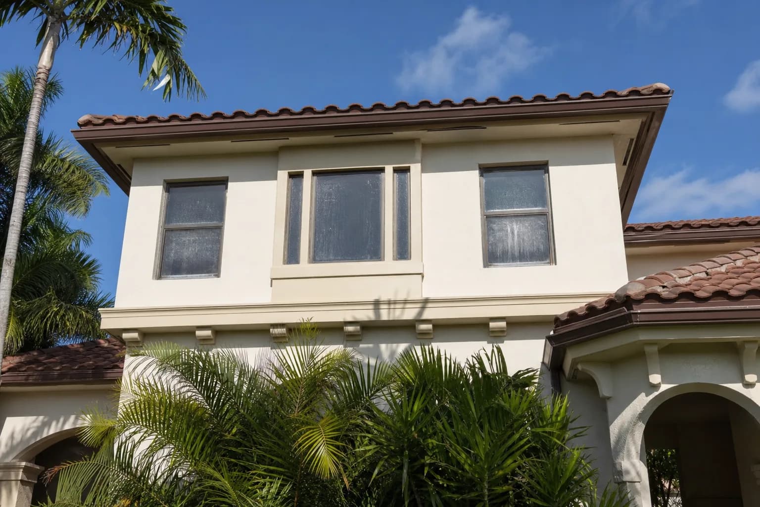 Second-floor windows of a two-storey home streaked and dirty